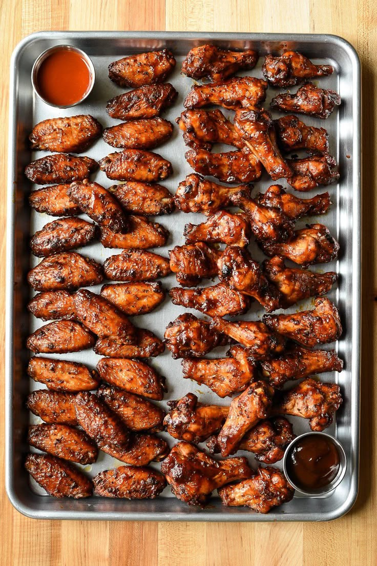 chicken wings on a tray with dipping sauce and ketchup in the middle, ready to be cooked