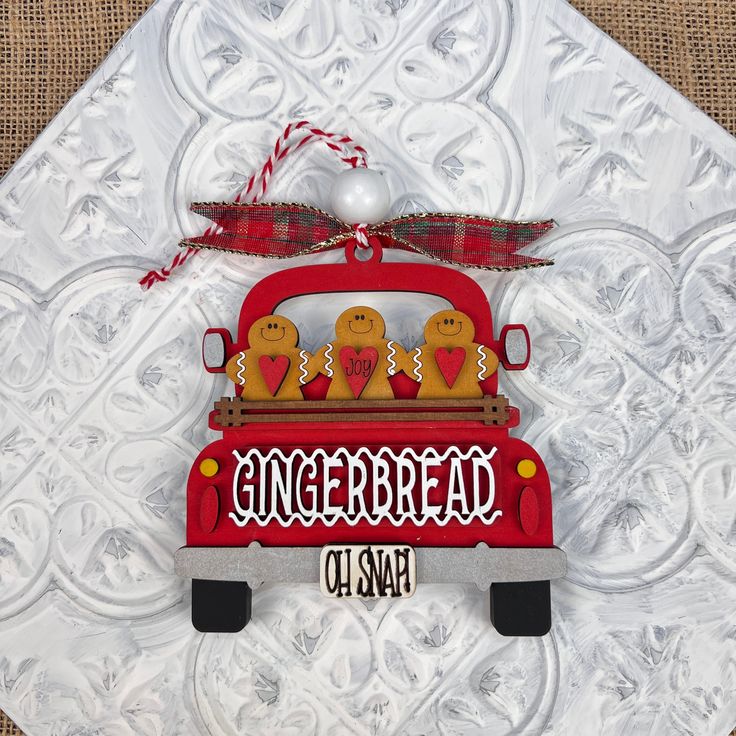 an ornament with gingerbreads in the back of a red truck on a white background