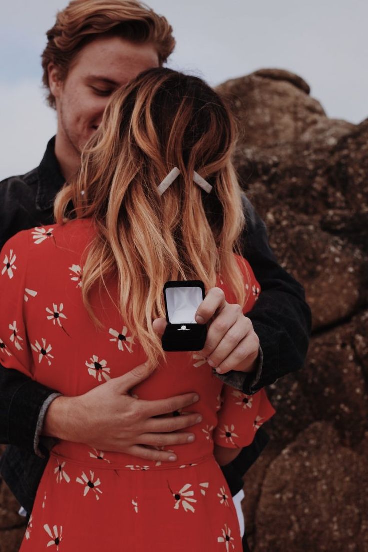 a man and woman embracing each other in front of rocks