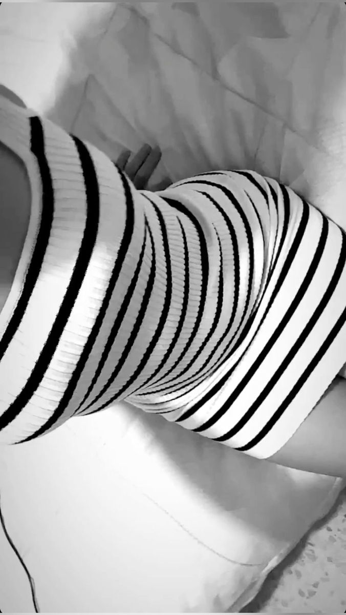 black and white photograph of woman's legs in striped tights with high heels