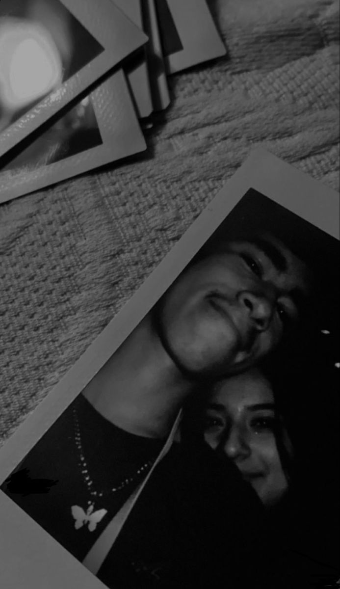 black and white photograph of two people on a bed next to each other, with three pictures in front of them