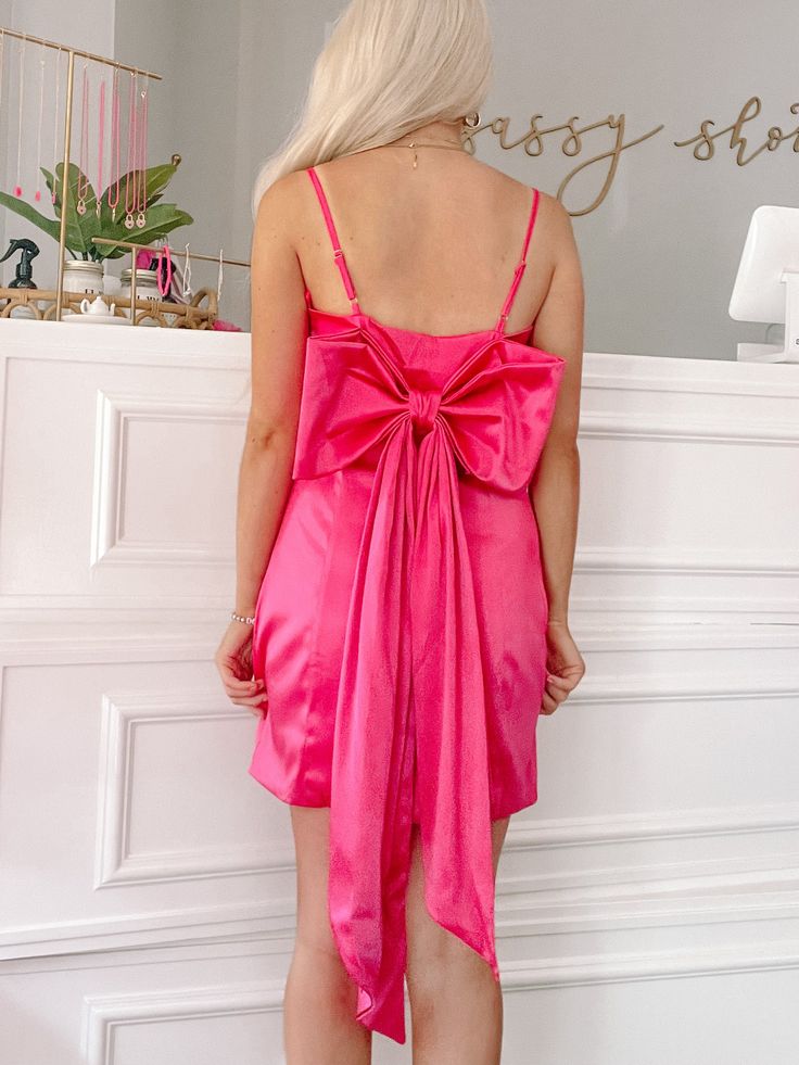 Meet the Malibow Barbie Dress from Sassy Shortcake. This hot pink pretty features silky material, adjustable straps, and a beautiful bow along the back. Fits true to size, Model wearing a size small. Pink Bow Dress For Brunch, Pink Satin Mini Dress With Bow, Pink Dress With Bow For Brunch, Pink Sleeveless Mini Dress With Bow Tie Back, Pink Bridesmaid Dress With Bow Tie Back, Pink Party Dress With Bow Tie Back, Flirty Pink Mini Dress With Bow, Chic Pink Mini Dress With Bow Tie Back, Pink Bow Tie Back Dress For Prom