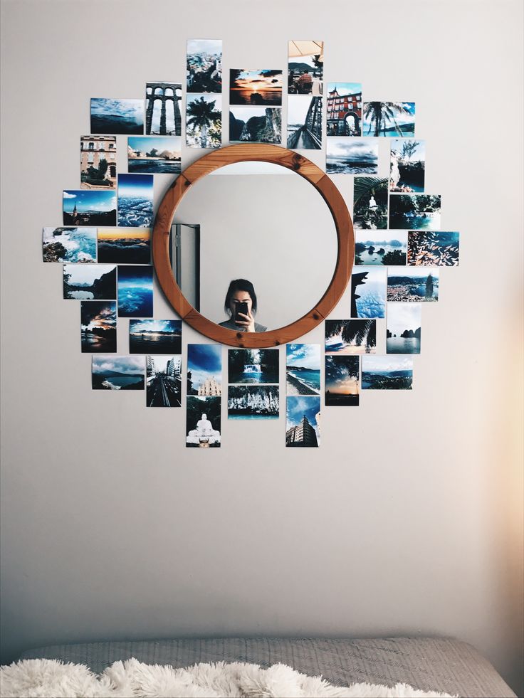 a circular mirror hanging on the side of a wall filled with pictures next to a bed