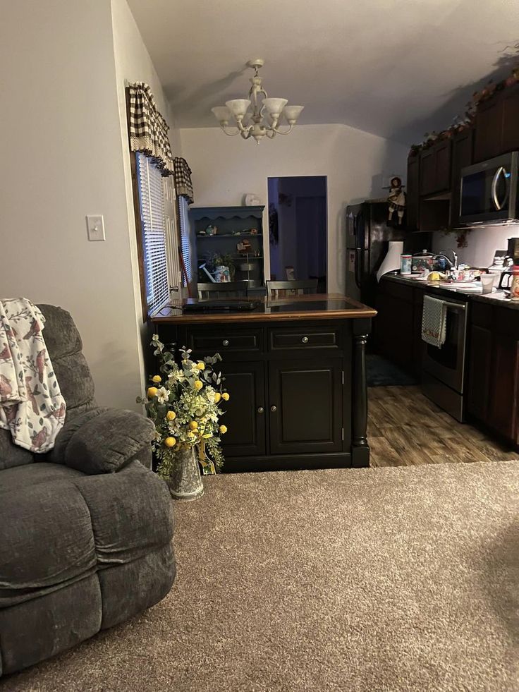 a living room filled with furniture next to a kitchen