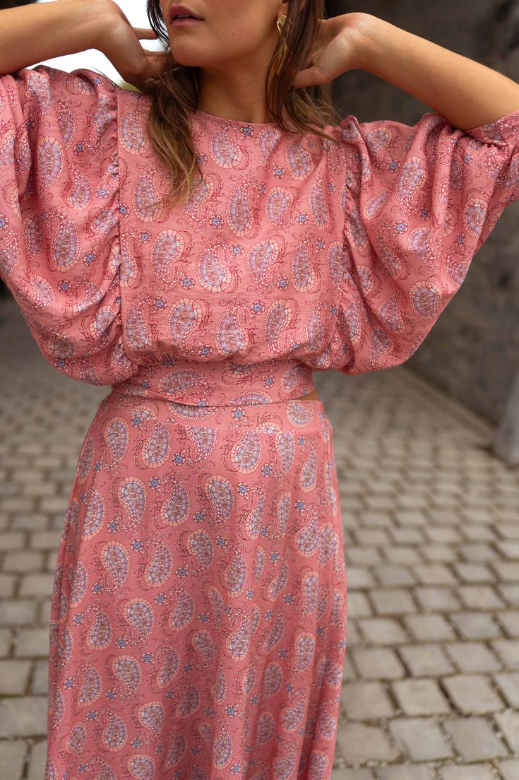 Perfect for dressing up or dressing down, our pink, paisley-patterned Karlou blouse is the ultimate summer wardrobe staple. Featuring a crewneck, a drawstring to tie on back, and 7/8th length balloon sleeves, this blouse is slightly cropped and totally adorable. Our model is also wearing the Larou skirt and Maddie jeans One size (fits from US 2-4-6-8) Length 18.5 in - Width 13.78 in 100% viscose Washing: handwash only Summer Crew Neck Top With Gathered Sleeves, Crew Neck Top With Gathered Sleeves For Summer, Pink Bishop Sleeve Blouse For Spring, Casual Tops With Bishop Sleeves For Summer, Casual Bishop Sleeve Tops For Summer, Casual Puff Sleeve Top With Bishop Sleeves For Summer, Spring Pink Tops With Elastic Sleeves, Summer Flowy Blouse With Bishop Sleeves, Flowy Summer Blouse With Bishop Sleeves