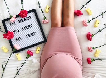 a woman laying on top of a bed next to flowers and a sign that says i'm ready to meet my pee