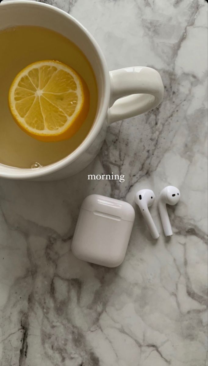 an apple airpods sitting next to a cup of tea with lemon slices on it