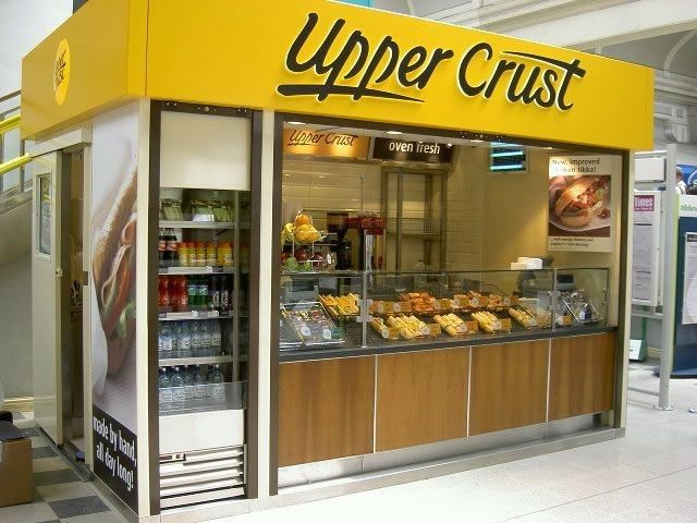 an upper crust bakery with lots of food in the display case and on the counter