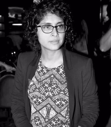 a black and white photo of a woman with glasses standing in front of a camera