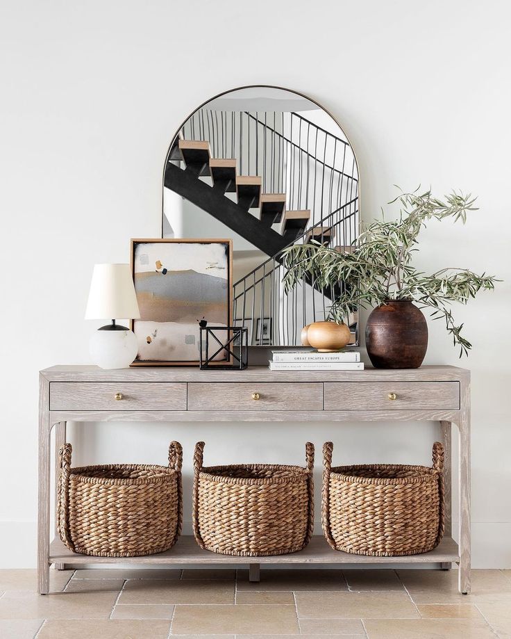 a table with baskets under a mirror and stairs