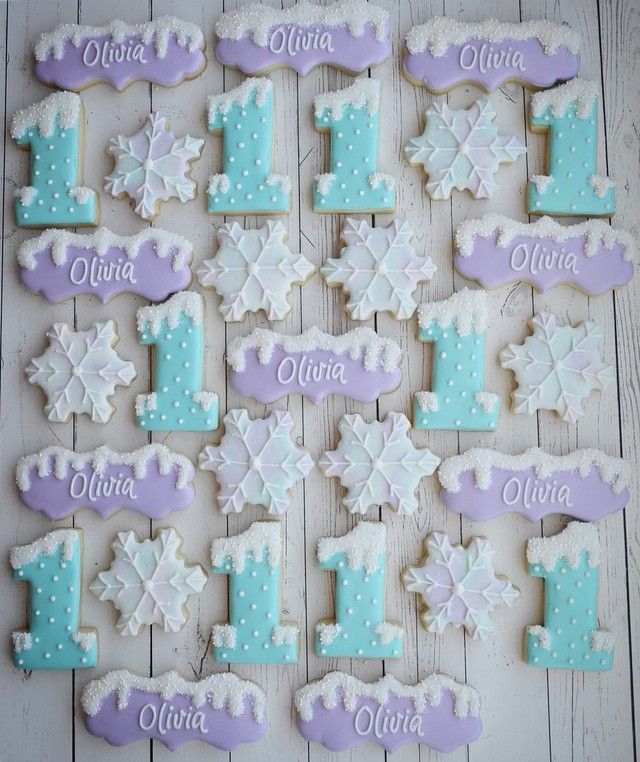 decorated cookies are arranged in the shape of snowflakes and numbers for first birthdays