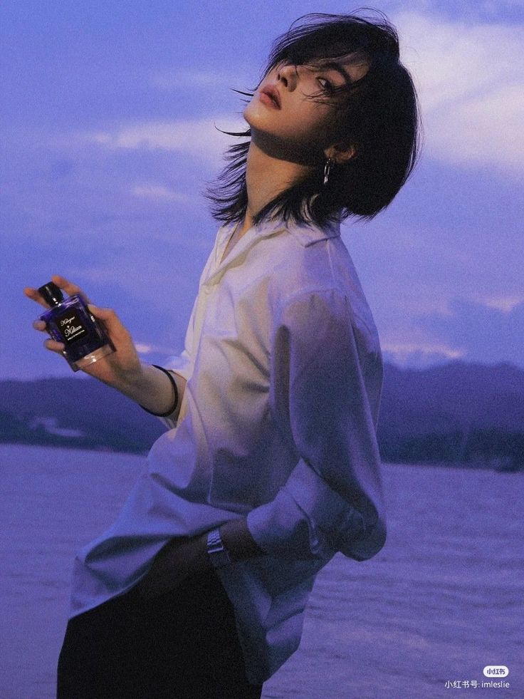 a woman standing by the water holding a bottle