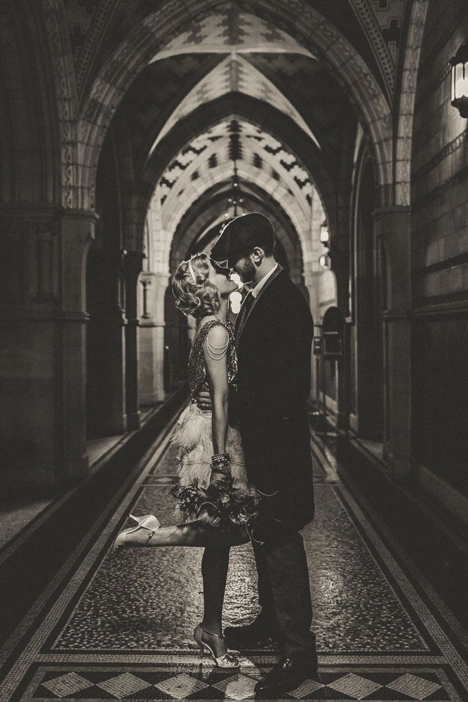 black and white photograph of a couple kissing in an old building with tiled flooring