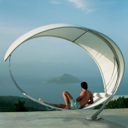 a man sitting in a chair on top of a roof next to the ocean and an island