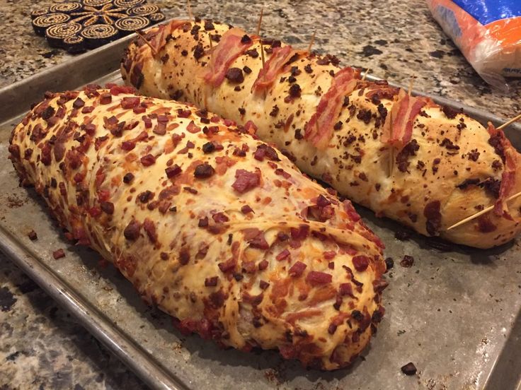 two pieces of pizza sitting on top of a baking pan covered in cheese and bacon