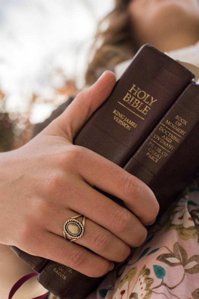 a woman is holding a bible in her hand and wearing a ring on her finger