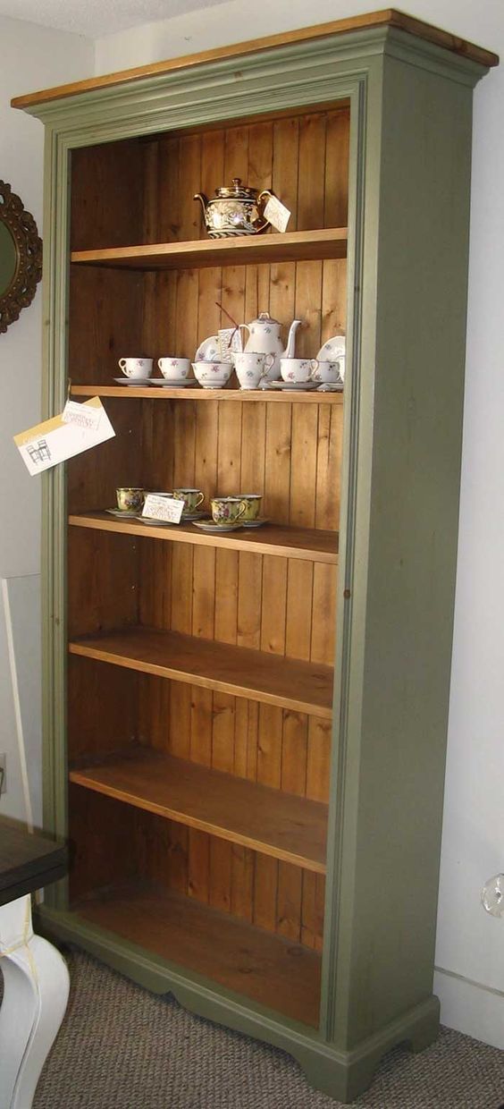 a green bookcase with tea cups and saucers on it