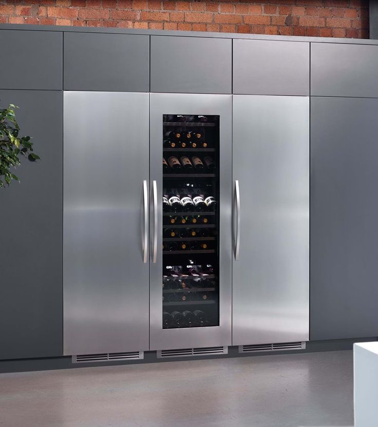 a stainless steel double door wine cooler in a kitchen with brick wall and grey flooring