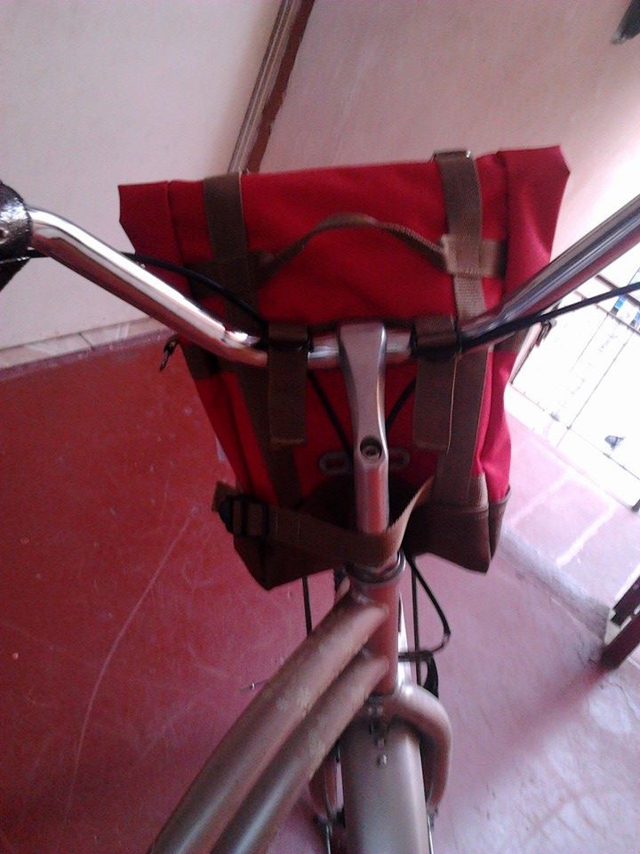 a bicycle with a red bag strapped to the handlebars and seatpost on it