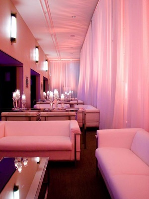 a room filled with white couches and tables covered in pink draping on the walls