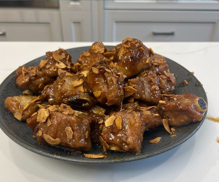 a plate filled with meat covered in sauce on top of a white countertop next to an oven