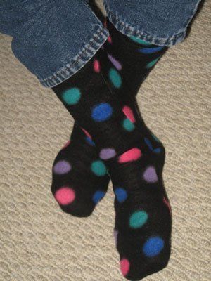 the feet of a person wearing colorful polka dot socks and blue jeans, standing on carpet