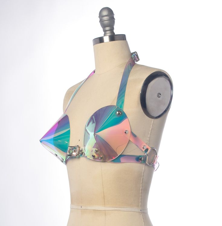 This bullet bra, or "cone bra" is inspired by retro pin-up vixens. This is the iridescent holographic version! Halter style straps. Buckles in front, back, and behind the neck. Silver-toned nickel plated hardware. Holes reinforced with grommets. Available in Sunset PVC (shown) or Blue PVC. Both colors are transparent. Sunset shifts warm over light colors, shifts blue over darker colors. Blue shifts cool over light colors, and warm over darker colors. Fits up to a DD cup - custom sizing available Bra Harness, Bullet Bra, Retro Pin Up, Dd Cup, Cone Bra, Halter Style, Make Time, Dark Colors, Bra Sizes