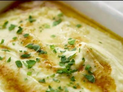 a casserole dish with cheese and green garnish