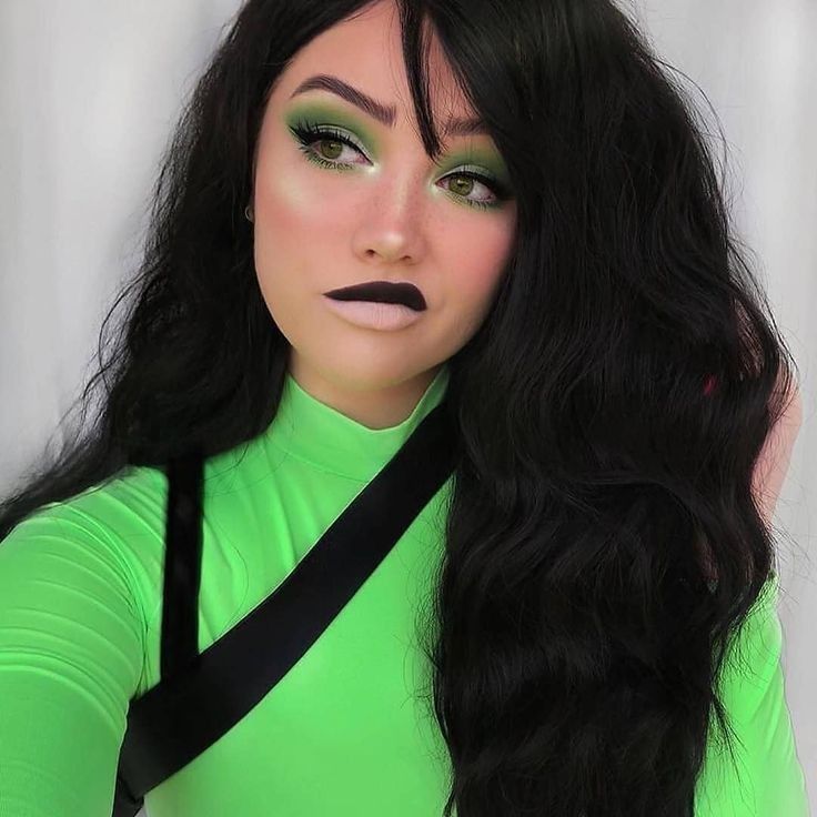 a woman with long black hair and green makeup