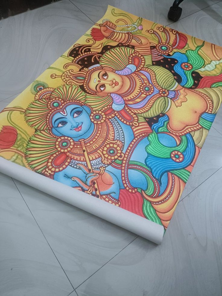 an artistic painting on the floor in front of a laptop computer case that is open to show it's artwork