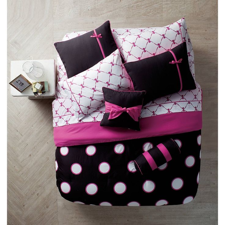 black and pink bedding with white polka dots on the comforter is next to an alarm clock