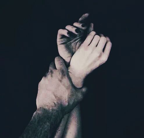 two hands holding each other in the dark