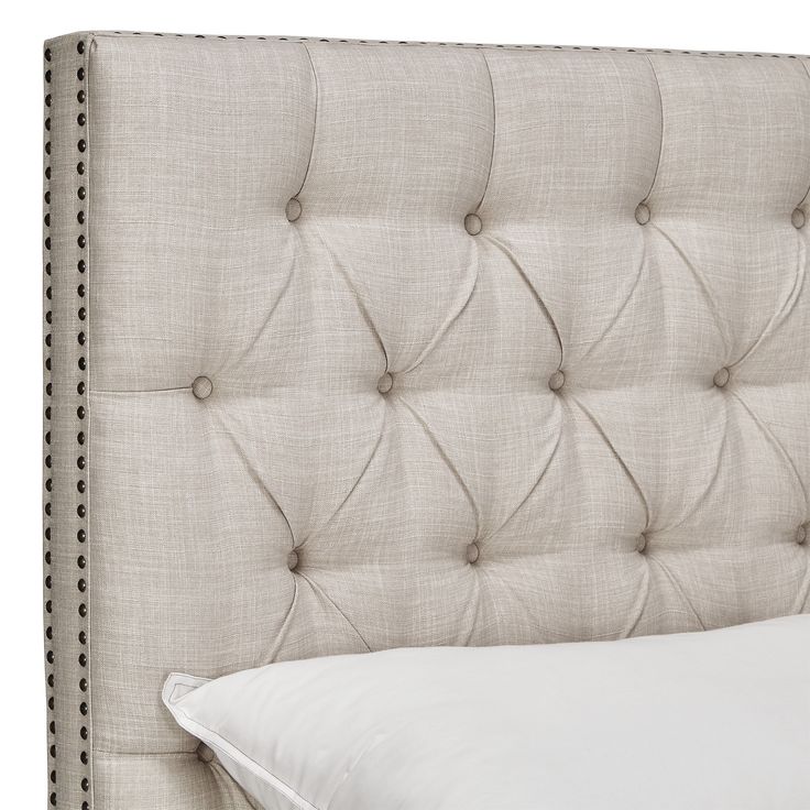 an upholstered headboard with buttons and studs on the sides, along with a white pillow