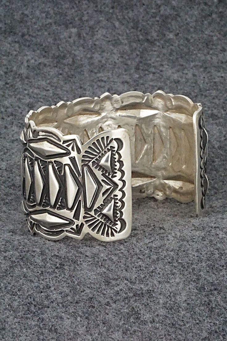 This sterling silver bracelet was made by Navajo silversmith Leander Tahe. The inside is signed L. Tahe and stamped sterling.Size: 6" (will fit up to a 7 1/4" wrist)Gap: 1 1/4"Width: 1 1/2"Free shipping on all orders! We ship with USPS and always include tracking. All orders ship within a day of payment.Returns are accepted up to 30 days after you receive your order. Just send us a message. Our shop offers cash back or store credit. The item must be returned in new condition. Southwestern Silver Bracelet Jewelry, Southwestern Style Silver Bracelet Jewelry, Southwestern Style 925 Silver Bracelets, Unique Adjustable Etched Sterling Silver Bracelet, Unique Etched Adjustable Sterling Silver Bracelet, Artisan Sterling Silver Bracelet With Etched Details, Handmade Southwestern Silver Bracelets, Unique Intricate Sterling Silver Bracelet, Southwestern Style Silver Bracelet