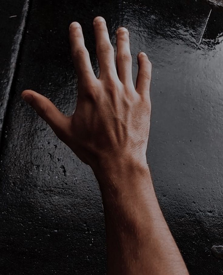 a person's hand reaching up to grab something out of the wet ground with their fingers