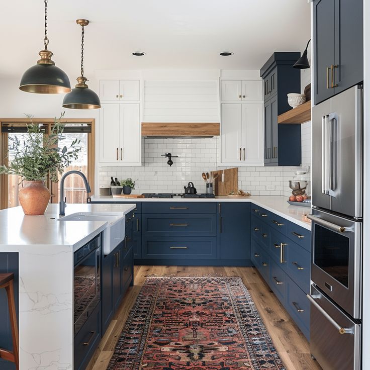 a kitchen with blue and white cabinets, an area rug and two pendant lights hanging from the ceiling