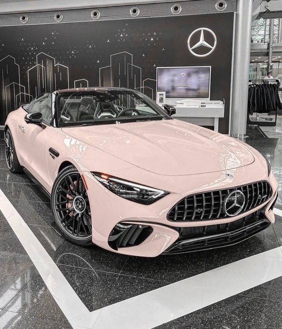 a pink sports car is on display in a showroom with black and white walls