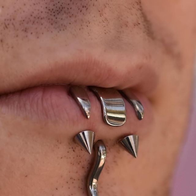 a close up of a person's nose with three metal spikes attached to it