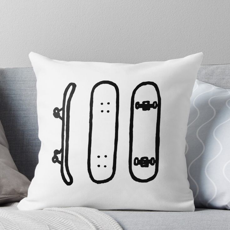 a white pillow sitting on top of a couch next to a gray throw pillow with two skateboards drawn on it