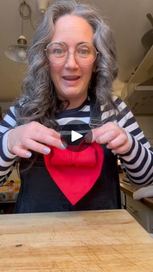 a woman wearing glasses holding up a heart shaped object