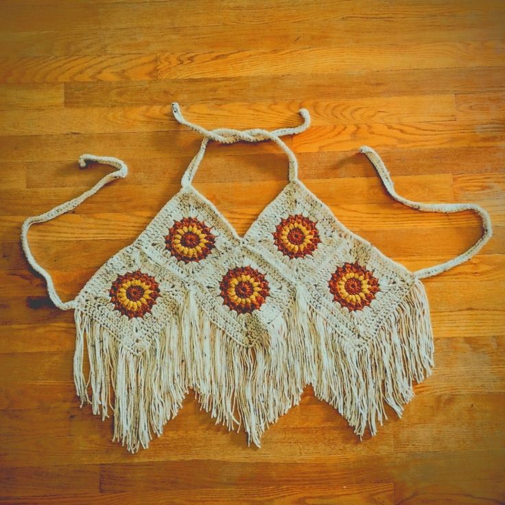 two crocheted purses with tasselled handles on a wooden floor, one is white and the other has orange flowers