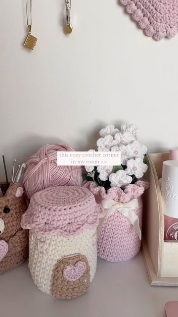 crocheted teddy bears and other items are displayed on a table with pink accents