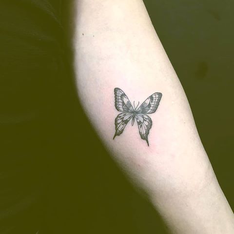 a woman's arm with a butterfly tattoo on the left side of her arm