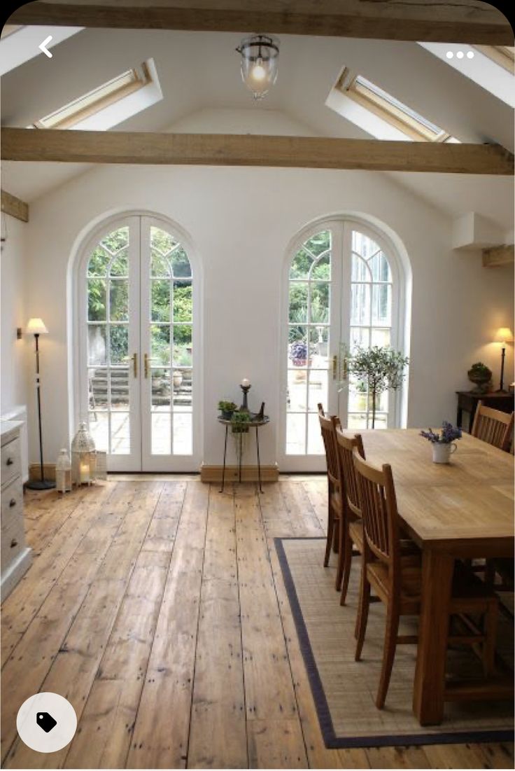 a large open kitchen and dining room area with wooden floors, white walls and vaulted ceiling