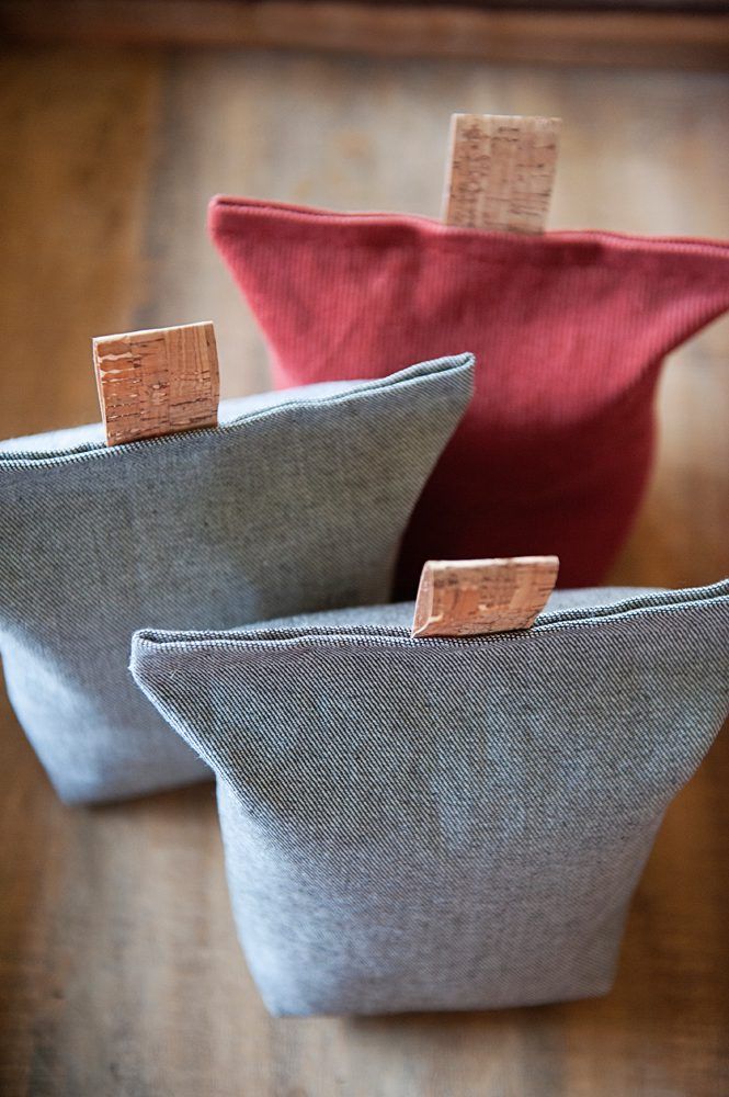 two small gray and red bags sitting on top of a wooden table next to each other