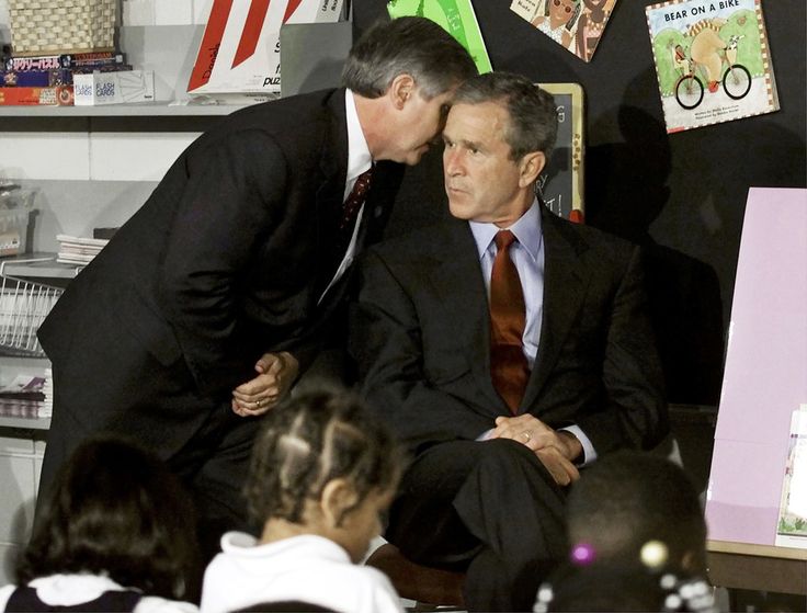 two men in suits and ties sitting next to each other at a table with children