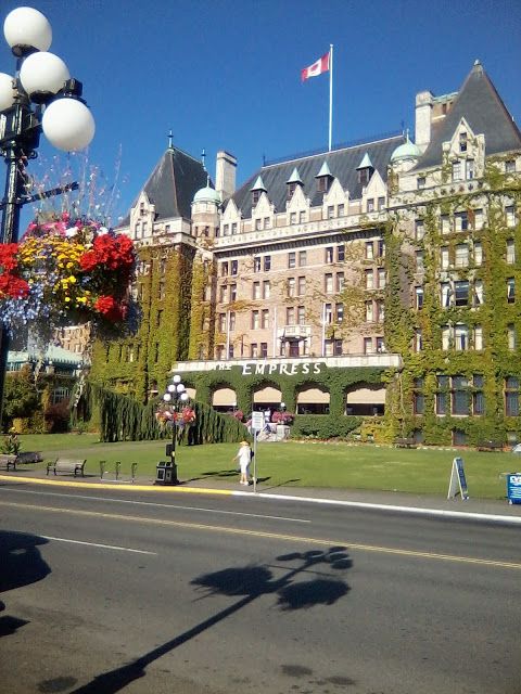 an old building with ivy growing on it's sides and people walking in front