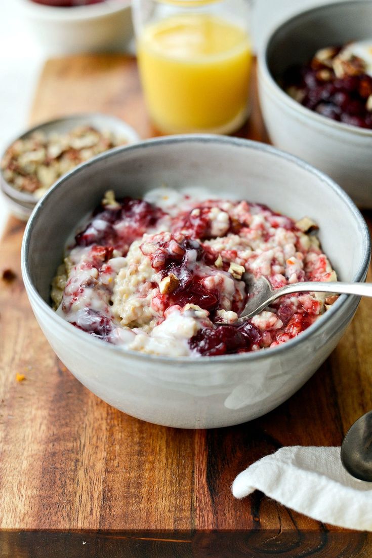 a bowl of oatmeal with fruit and nuts in it on a wooden cutting board