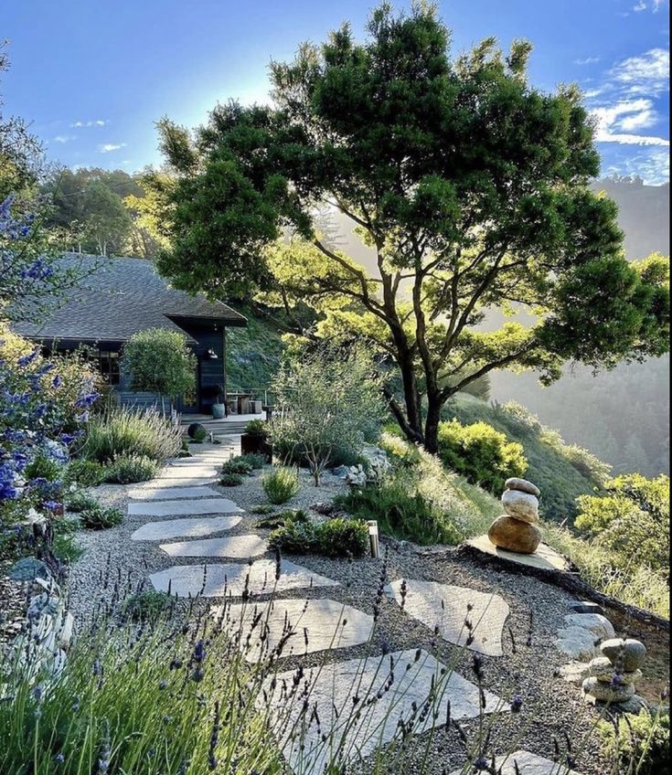 a stone path leading up to a house on top of a hill surrounded by trees