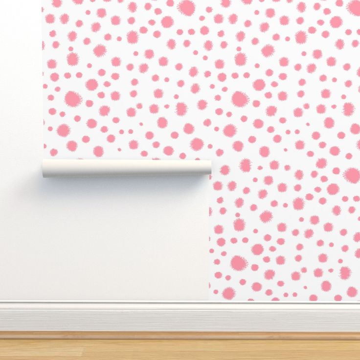 a white wall with pink and red polka dots on it, next to a wooden floor